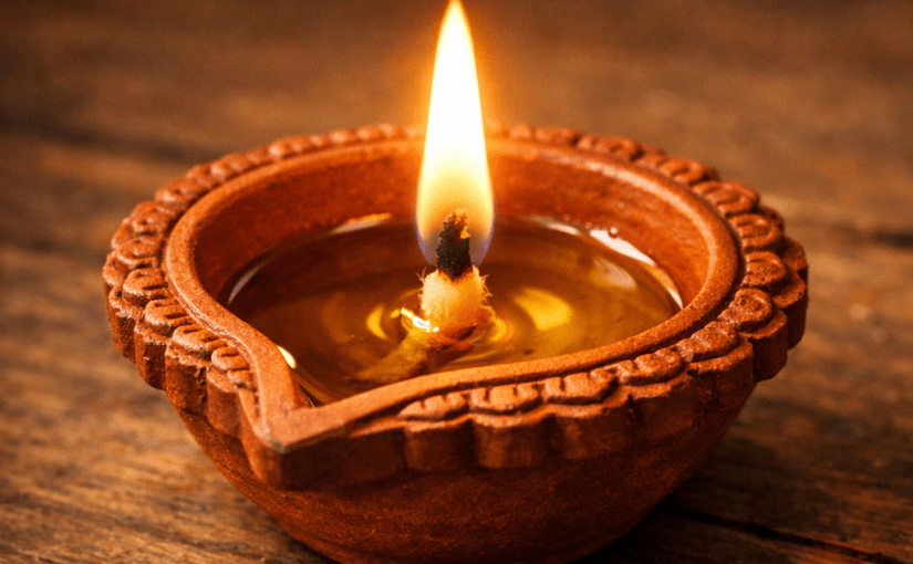 Lit traditional clay oil lamp filled with oil and cotton wick